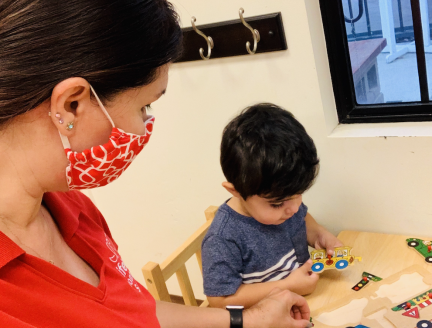 Toddler playing with puzzles while Montessori Teacher provides guidance