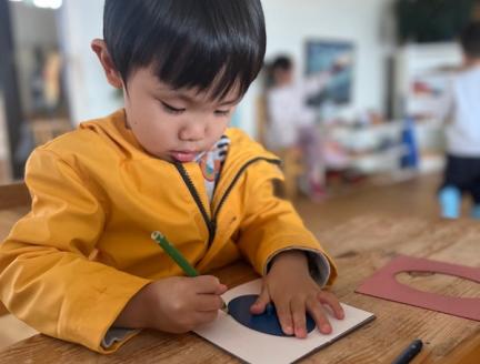 Child drawing a circle with a stencil benefits fine motor skills development