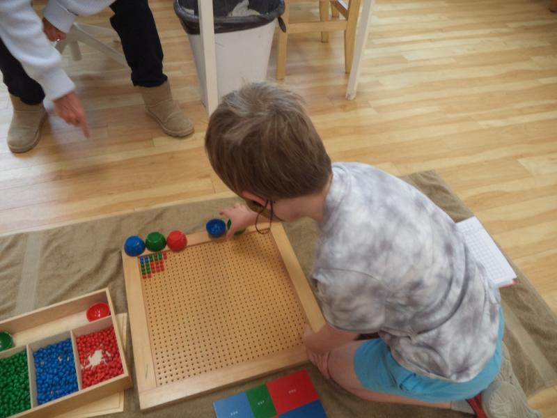 Boy Learning math in a Montessori Classroom with Teacher guidance