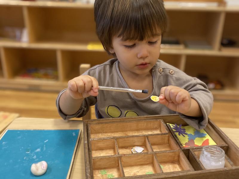 Preschooler in a Montessori classroom gluing with a paint brush