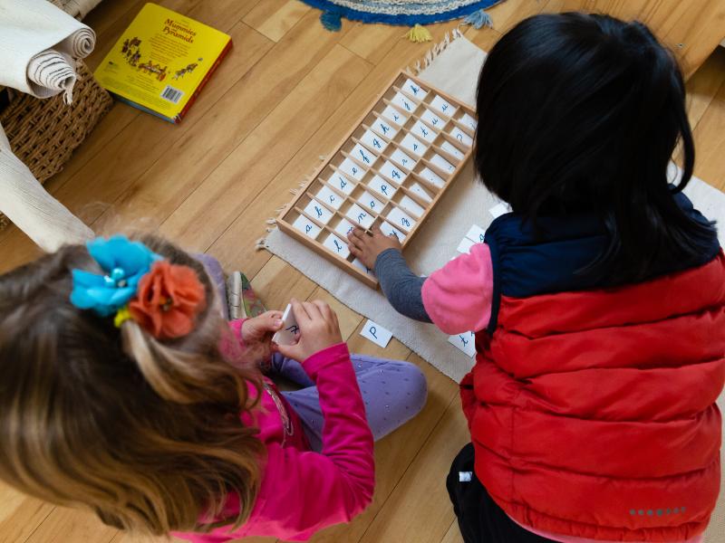 Boy and girl socializing while learning to spell in their Montessori classroom