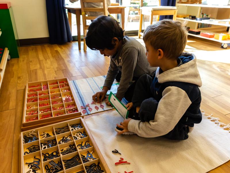 Two Boys using cursive letters to write in Montessori Classroom