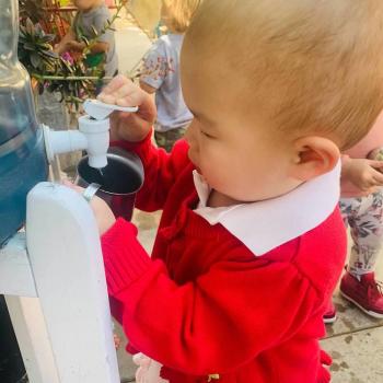 Toddler independently gardening and pouring water from a spout at Lifetime Montessori School 