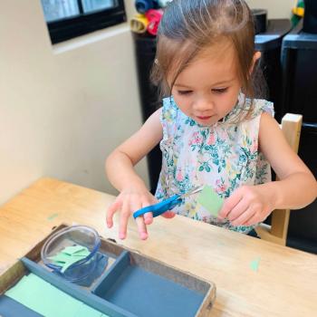 Toddler independently cutting with scissors at Lifetime Montessori School 