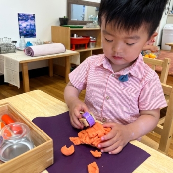 Toddler independently playing with dough at Lifetime Montessori School 