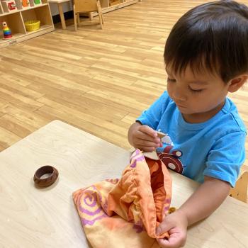 Toddler independently putting wooden tools in a bag at Lifetime Montessori School 